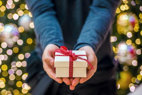 man wearing black shirt holding a christmas gift box. Man holding a gift box, giving someone present. Positive human emotion facial expression feeling attitude life perception